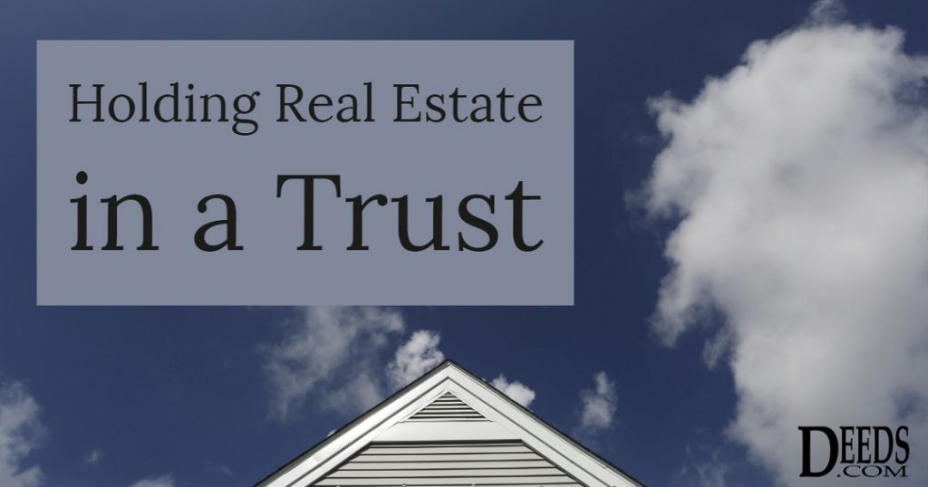 Image of the peak of a house with a blue sky background and fluffy clouds. Captioned: Holding Real Estate in a Trust.