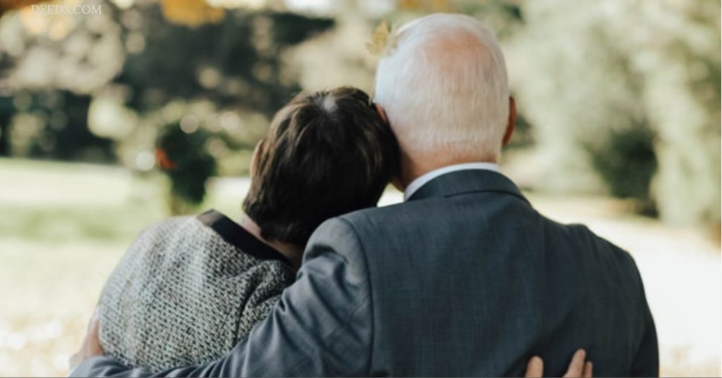 Image of a mature couple standing side by side arms holding each other's back, seemingly somber in mood. Presumably contemplating what happens if their mortgage outlives them.