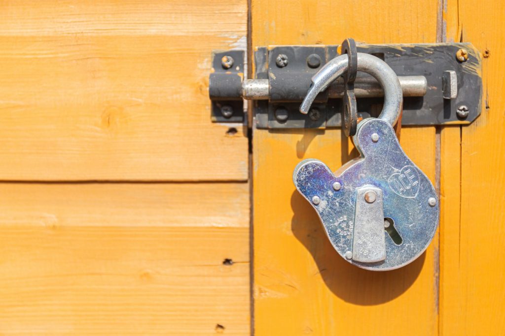 Image of an open lock hanging on a closed door latch.