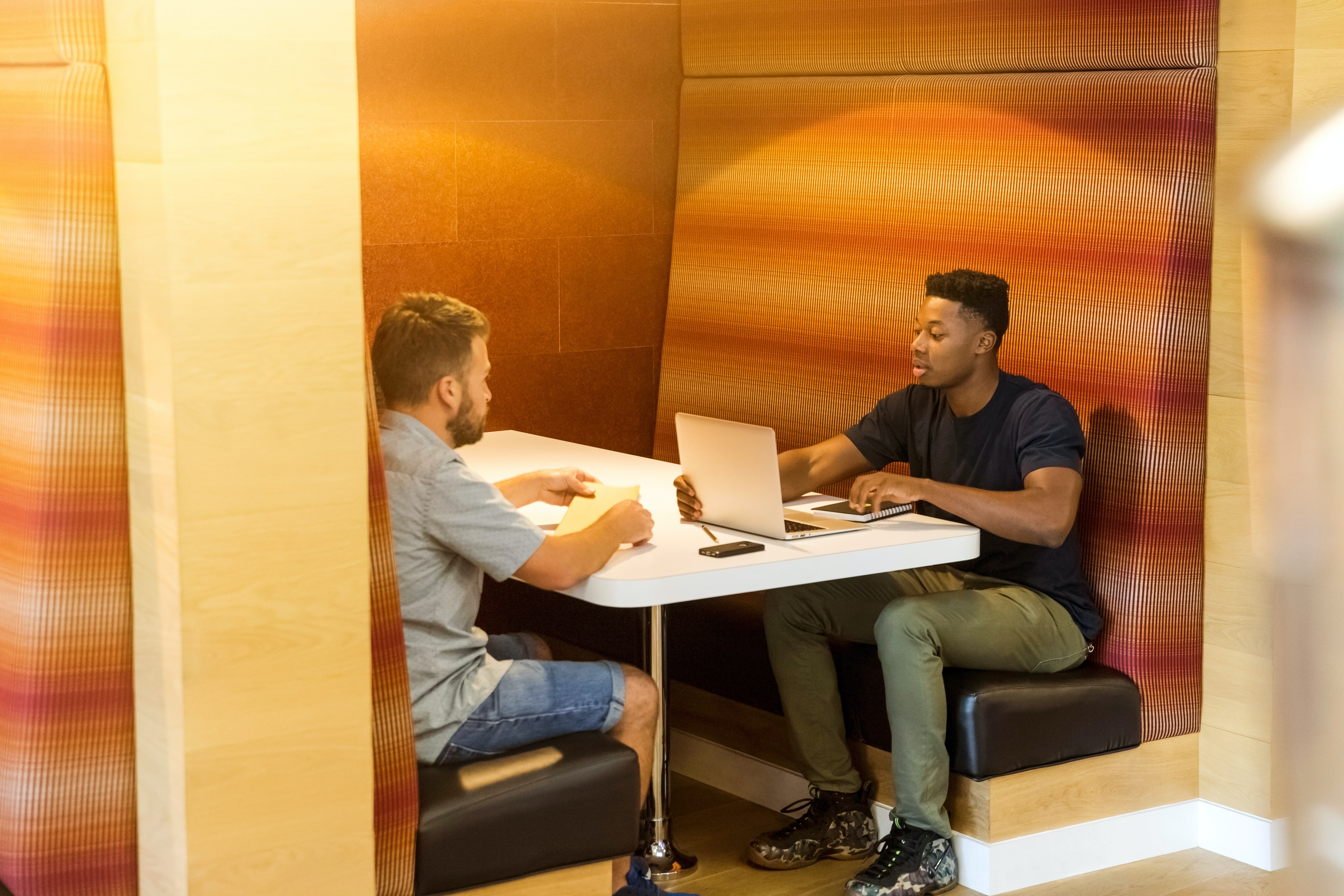 Two people sitting at a table with a laptop discussing real estate deeds.