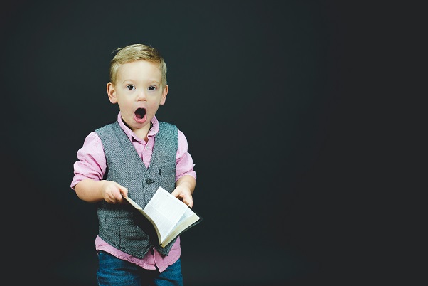 Image of a child holding a book with a very surprised like on their face. Captioned: When you least expect it... What You Need To Know About Unrecorded Real Estate Liens