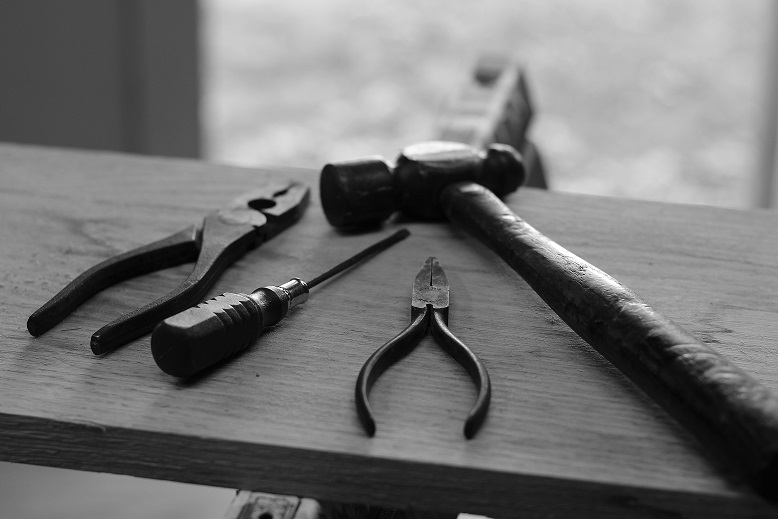 Image of woodworking tools laying on a board with a blurry background. Captioned: How to File a Mechanic's Lien