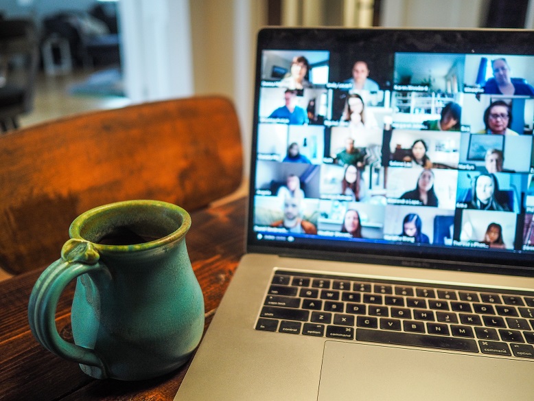Image of a computer sitting on a desk next to a cup of coffee in a home. Captioned: Working From Home May Impact Real Estate Buyer Preferences.
