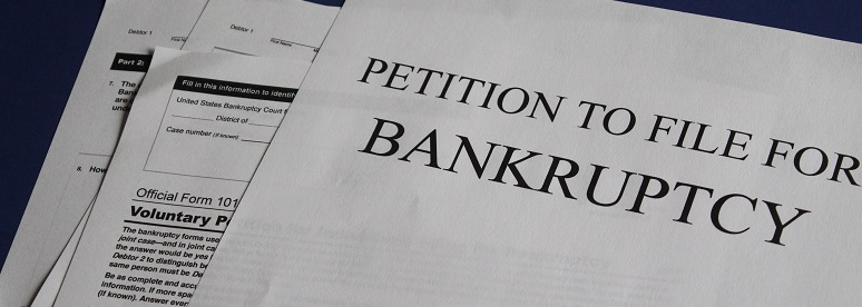 Image of bankruptcy documents scattered on a table. Captioned: Can Filing for Bankruptcy Save a Home From Foreclosure?