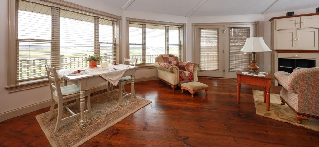 Image of the inside of a house with furniture and lots of windows looking outside. Captioned: Maintaining Your Home’s Value