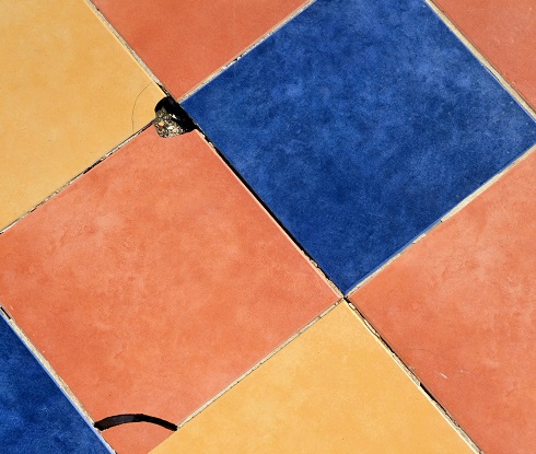 Image of colorful floor tiles with some broken or chipped and bad grout.