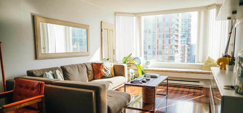 Picture of a small furnished living room with a big window looking outside. Captioned: A Guide to Private Mortgage Insurance