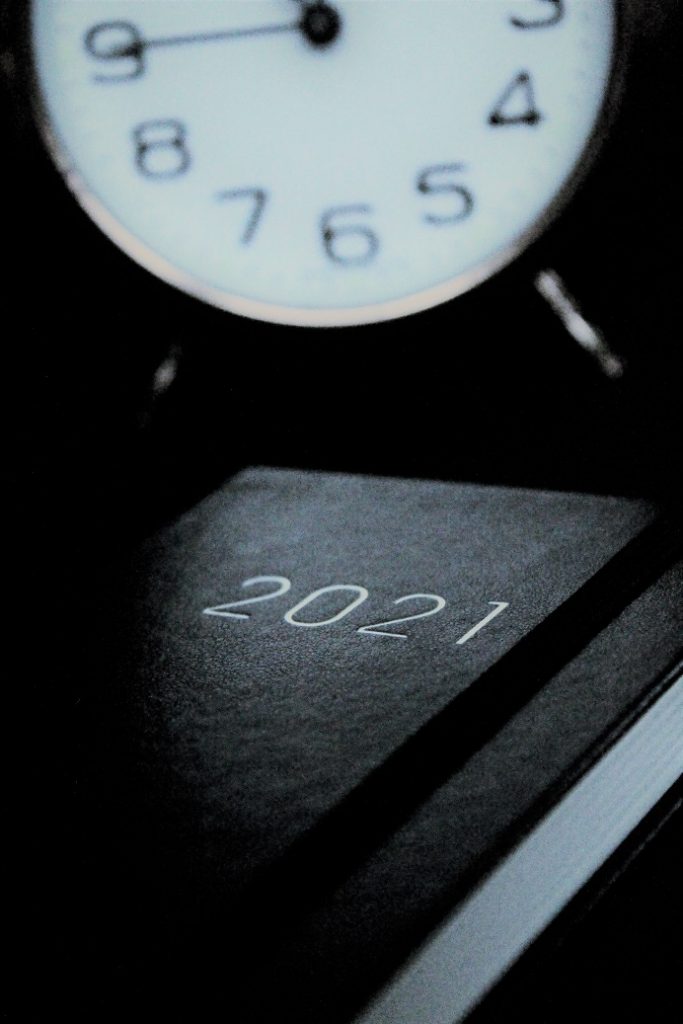 Dark image of a clock and a calendar planner for 2021.