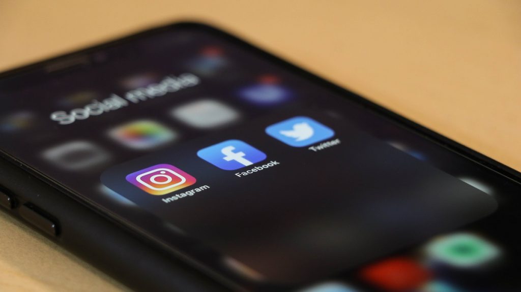 Image of the screen of a smart phone with social media icons showing. Captioned: Social Media Influence and Real Estate
