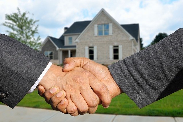 Close up image of two hands embraced in front of a house.