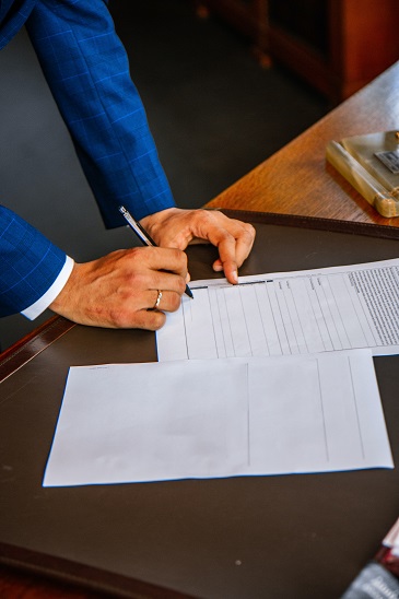Image of a person signing documents and going of a checklist. Here is a checklist of QPRT questions to present to your CPA and your estate planning attorney