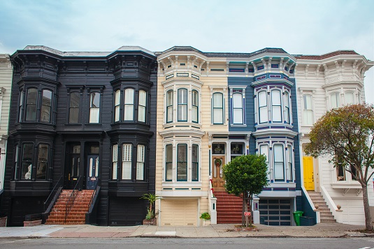 Image of the front of a row of tall houses in an urban setting.