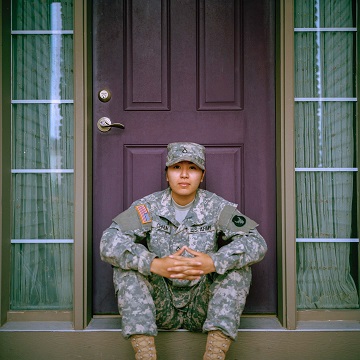 Image of a soldier sitting on the front steps of a home. Welcome home veteran.