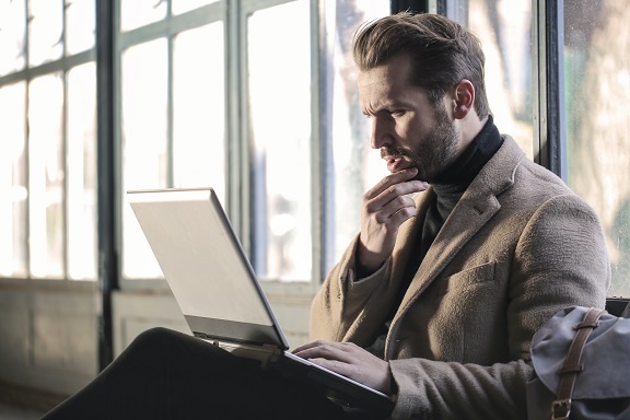 Image of a person in deep thought looking at a computer. Captioned: Interest Rates Are Low. Does That Make Refinancing a Good Deal?