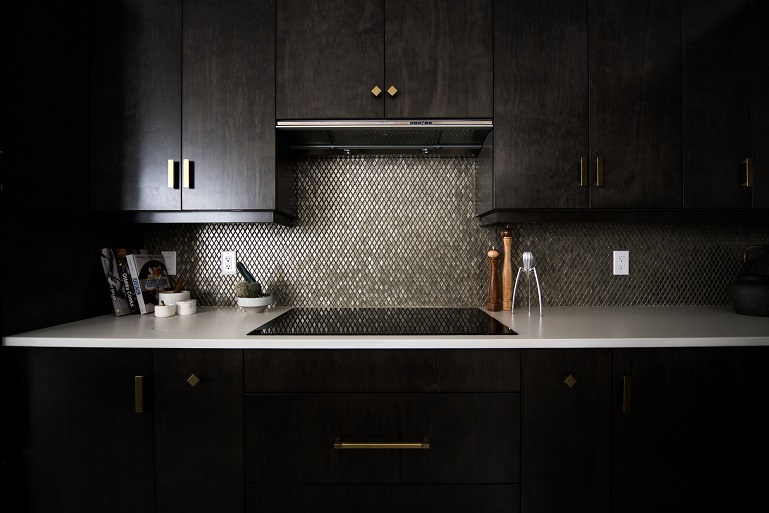 Image of a residential kitchen area, sink, counter, and cabinets. Dark lighting with no windows.