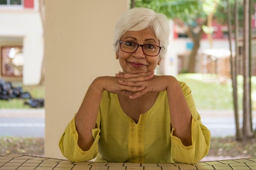 Image of a person resting their head on their folded hands looking at the camera. Captioned: Age at Home, Your Way
