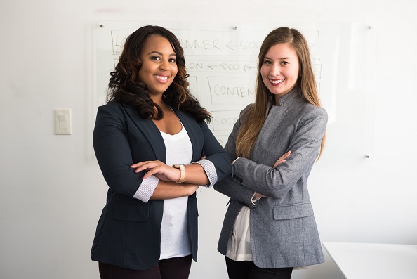 Two people, presumably real estate agents, standing next to each other, smiling, with arms crossed. Captioned: The Agent’s Perspective