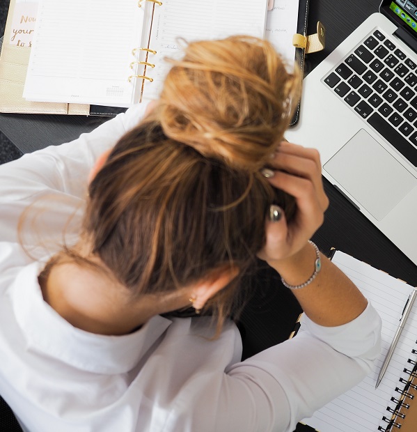 Image of a frustrated person hunched over a desk with their head in their hands. Captioned: Buying or Refinancing? Mortgage Servicing Matters.