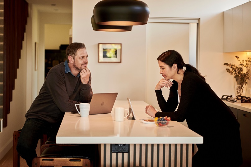 Image of two people leaning on a table looking at computers. Captioned: Notaries Go Remote: A Digital Shift Is Changing Notary Language