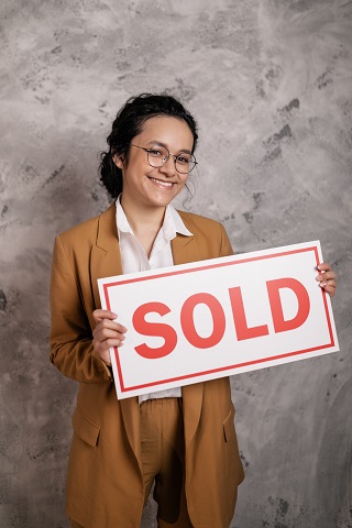 Image of a person holding a sold sign.