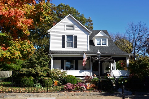 Image of the outside of a house, lots of mature landscaping, likely during the fall as the leaves are changing colors.