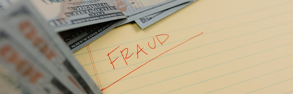 The word "Fraud" written in red ink on a piece of legal paper surrounded by some U.S. paper currency. Captioned: Closing Scams Now Make Up Nearly Half of Cybercrime Losses