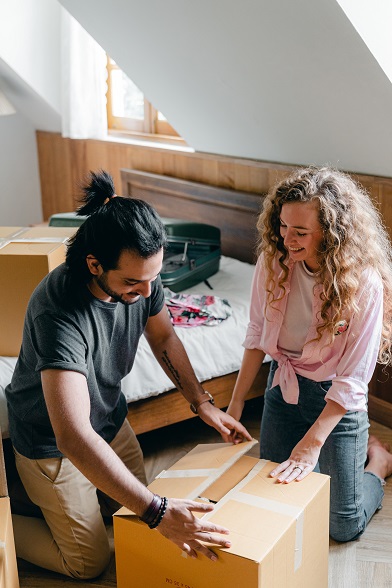 Image of two people opening and unpacking a moving box inside a new house.