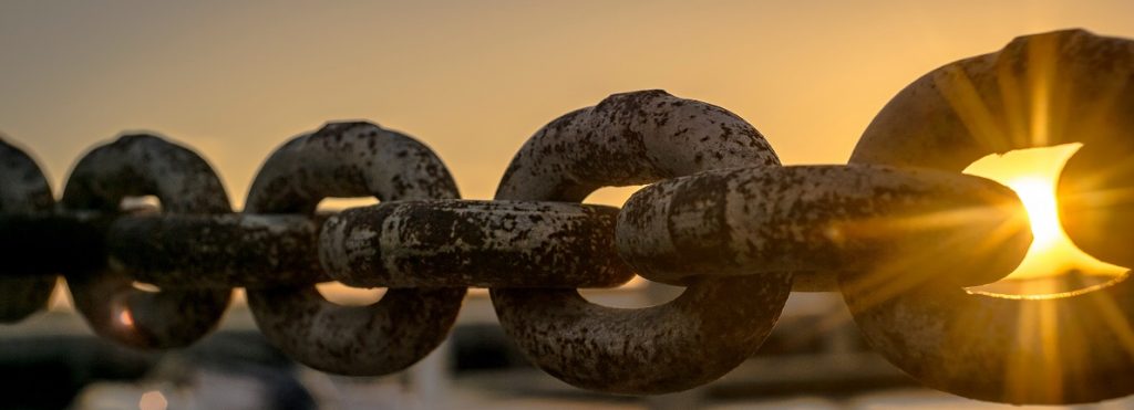 Image of a very large steel chain with the sun shining through one of the links. Captioned: Is a New Day Dawning for the Chain of Title?