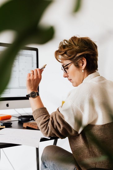 Person doing paperwork on a desk in front of a computer. Captioned: Perfecting (Real Estate) Property Values