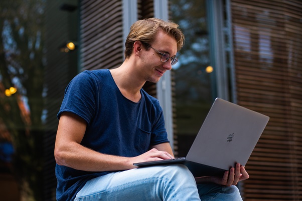 A person sitting outside looking at and typing on a laptop computer. Captioned: Should You Get an Adjustable-Rate Mortgage?