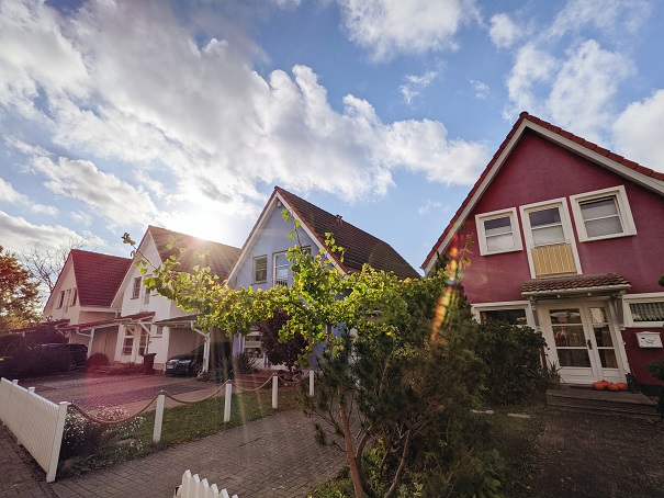 Image of a row of houses backlit by the sun with fluffy clouds in a mostly blue sky. Captioned: The Rise of the Property Tax Protests