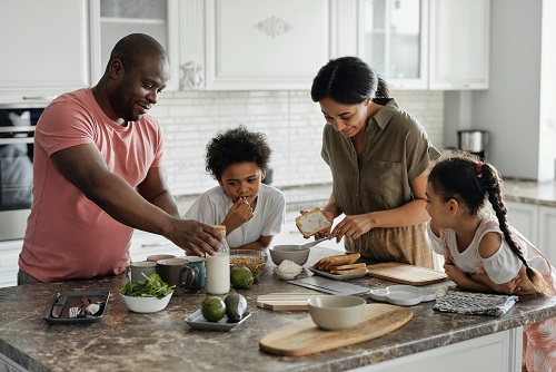 Happy family gathered in a kitchen preparing food. Captioned: Administration Confronts Racial Bias in Appraisals