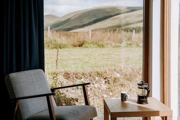 Image of furniture in a house and the view out a window to a mountainous scene.