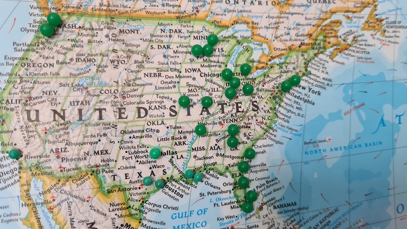 Image of a map of the United States with green pushpins marking locations of foreign real estate investing.