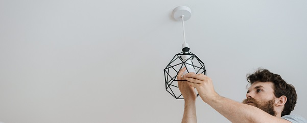 A person working on a light hanging from the ceiling. Captioned: What you should know about selling your home as-is