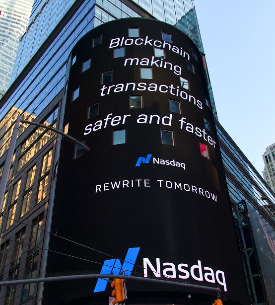 Image of the Nasdaq billboard with a city scape in the background. Captioned: Blockchain in Payments and Real Estate Transactions.