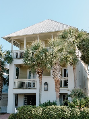 Image of a tall house with palm trees in front.