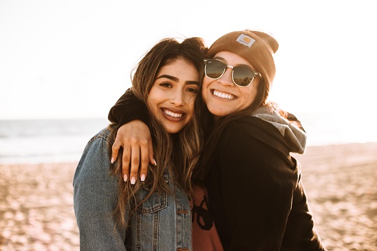 Image of two people seemingly happy while hugging on the beach.