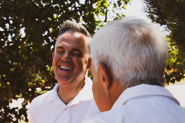 Two people standing outside laughing, sun is shining through the trees. Captioned: Real Estate Fraud Happens. Protect Yourself.