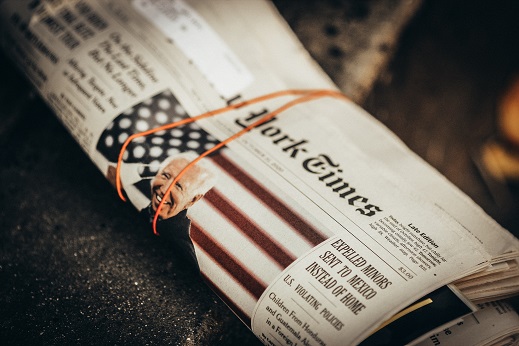 Image of a rolled up news paper with a rubber band around it.