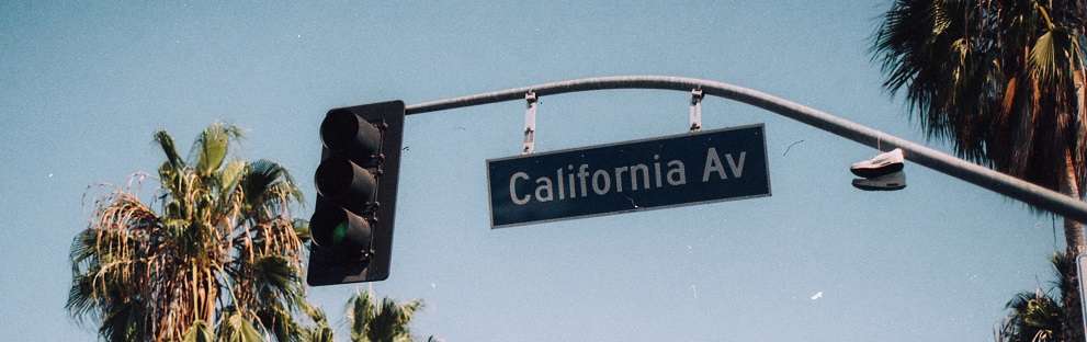 Image of a street sign reading "California Av" with blue sky and palm trees in the background.