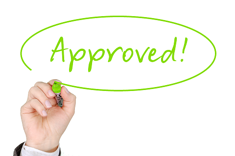 Image of the word Approved written on a glass board in green by a hand holding a green pen.