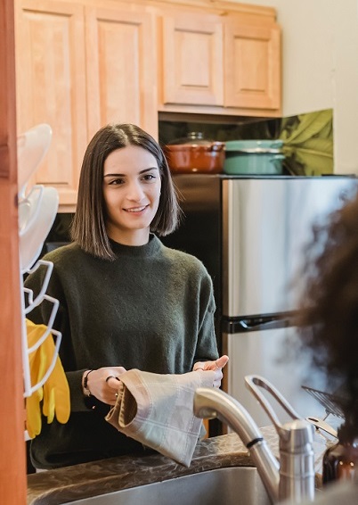 Person at a kitchen sink talking to another person about the housing boom.