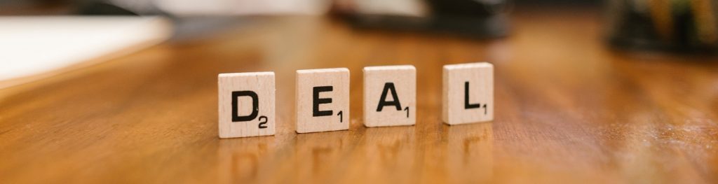 Small wood tiles with letters on them stood on a table spelling out the word DEAL