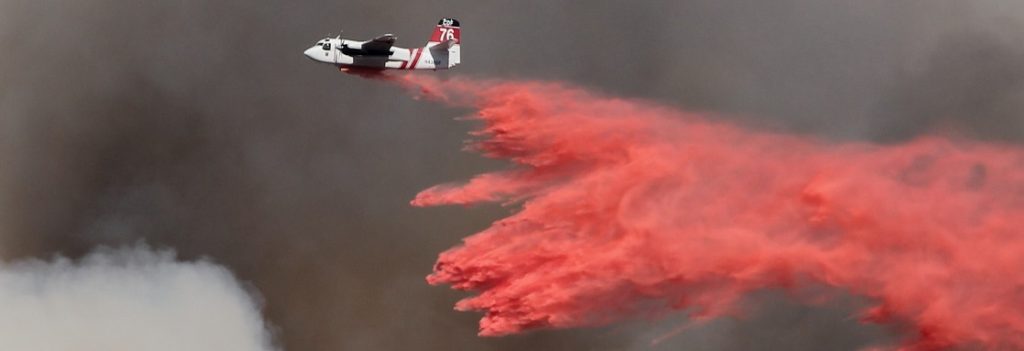 Airplane dropping fire fighting chemicals on a wildfire.