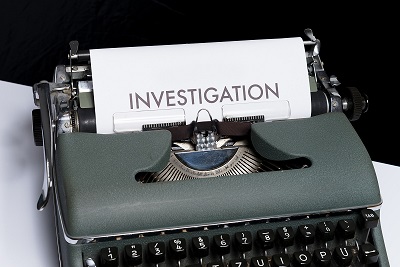 The word "investigation" typed on paper in an old type writer.