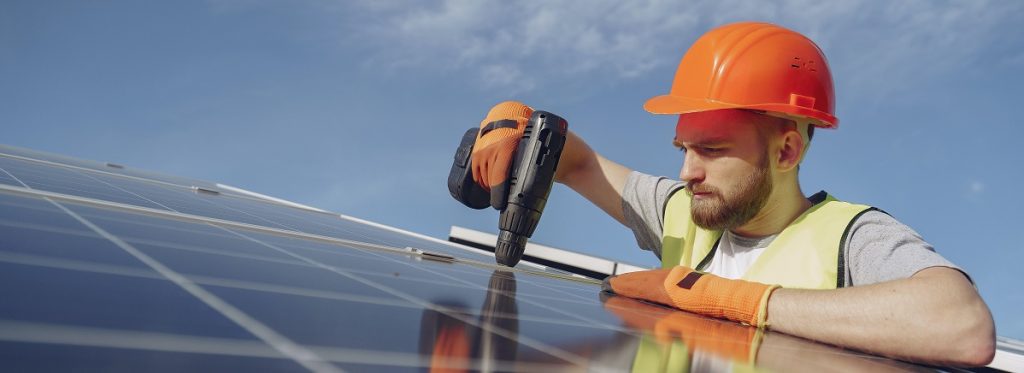Person working on solar panels on top of a house.