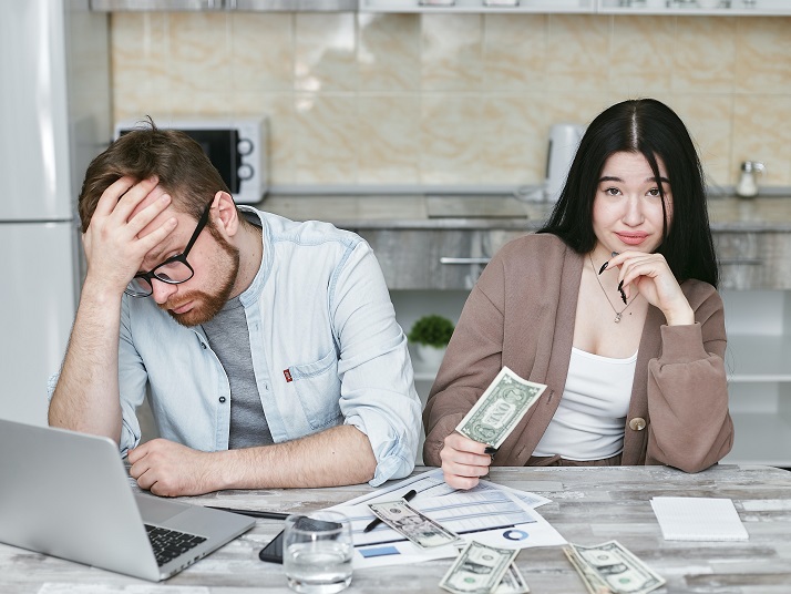 Two people sitting at a table looking stressed over money
