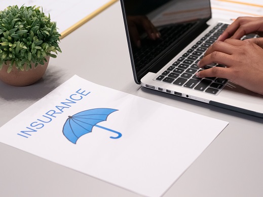 Image showing hands using a computer keyboard with insurance paperwork sitting on the table.