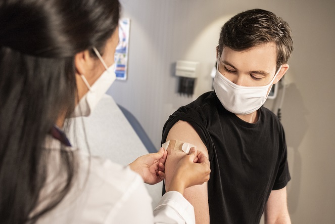 Person getting a vaccine shot in their arm by a medical professional.